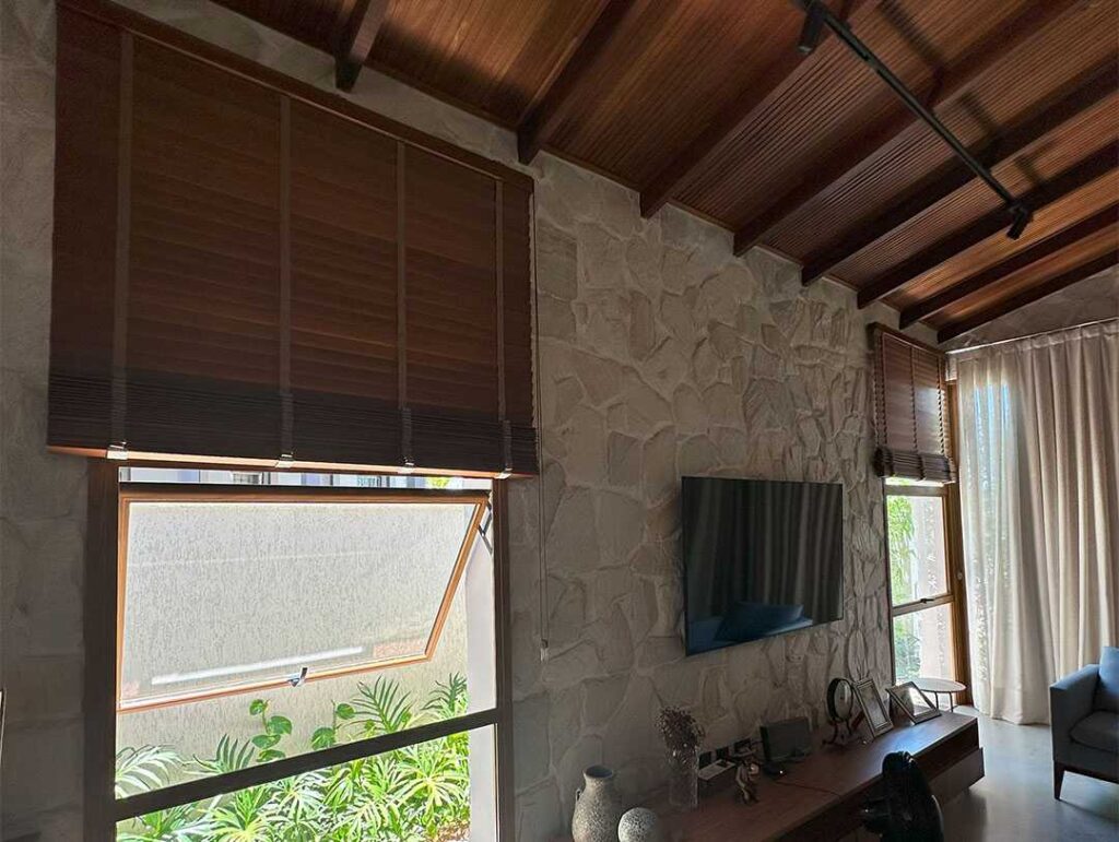 Persiana horizontal de madeira e cortina voil em sala com cobertura de madeira